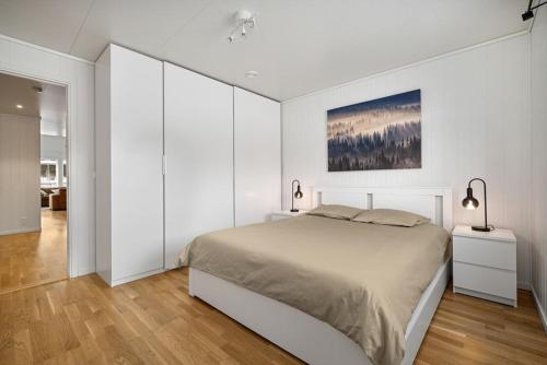 a white bedroom with a large bed in a room at Moderne enebolig in Røros