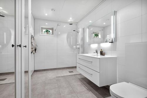 a white bathroom with a shower and a toilet at Moderne enebolig in Røros