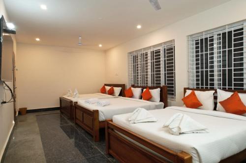 a bedroom with two beds and two windows at Unique ajvi Resorts inn Yercaud in Yercaud