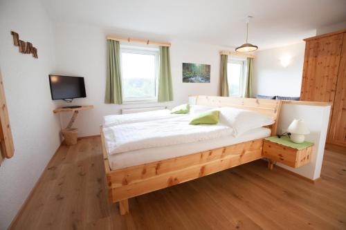 a bedroom with a wooden bed and a television at Beim Einfalt B&B in Grossgerungs