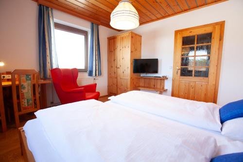 a bedroom with a large white bed and a red chair at Beim Einfalt B&B in Grossgerungs