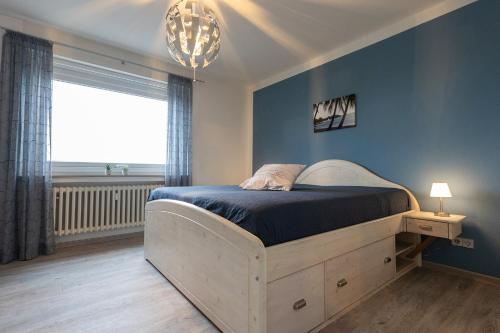 1 dormitorio con 1 cama con pared azul en FeWo Tecklenborghaus en Bremerhaven