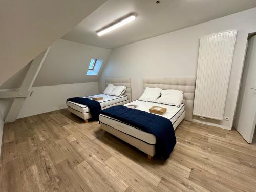 two beds in a small room with wood floors at Superbe Maison de maître 10 chambres 300 m2 Caen in Bretteville-sur-Odon