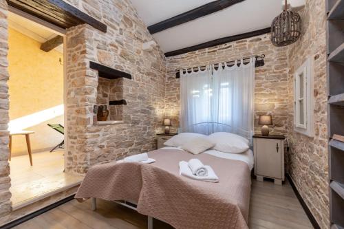 - une chambre avec un lit et un mur en briques dans l'établissement Rustic holiday house with jacuzzi, 4 Seasons, à Pazin