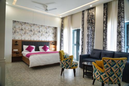 a bedroom with a bed and a couch and chairs at HOTEL GRP INN CITY HOME in Pithorāgarh