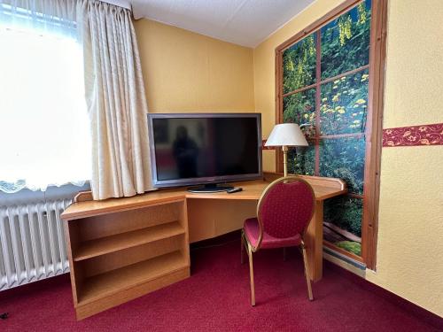 een kamer met een bureau, een televisie en een stoel bij Gasthaus zur Schwarzen Olive Zimmer 12 in Erlangen