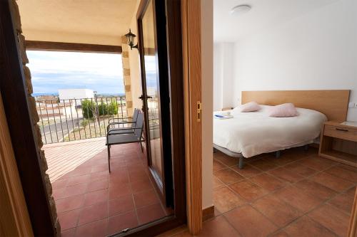 1 dormitorio con cama y vistas a un balcón en CASA GALEX, en Sarrión