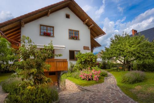 une maison blanche avec des fleurs devant elle dans l'établissement Apartmaji Volf, à Zgornje Gorje