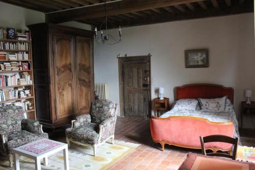 a bedroom with a bed and a chair and a book shelf at Maison de Noble Nicolas in Avallon