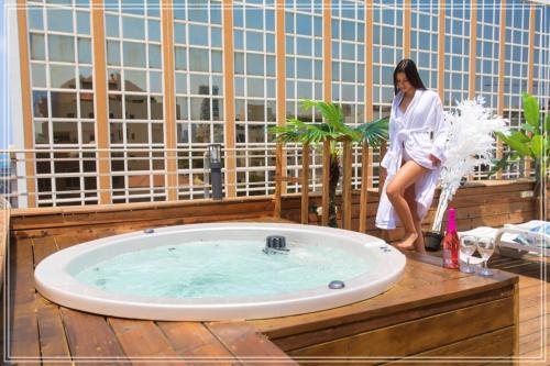 a woman sitting on a deck with a hot tub at Dream Beach 98 Hotel And Spa - Affordable Seaside Choice 2025 in Tel Aviv