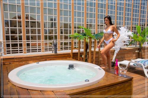 Dream Beach Hotel And Spa في تل أبيب: امرأة في البيكيني تقف بجوار حوض استحمام ساخن