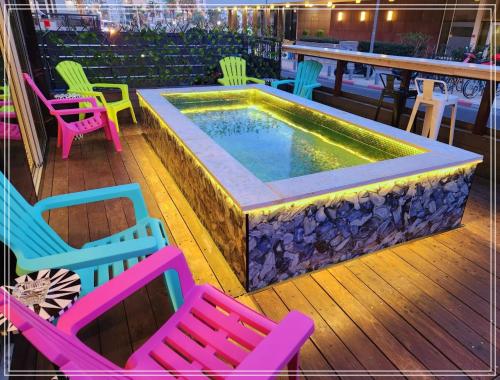 a pool sitting on a deck with colorful chairs at Dream Beach 98 Hotel And Spa - Affordable Seaside Choice 2025 in Tel Aviv