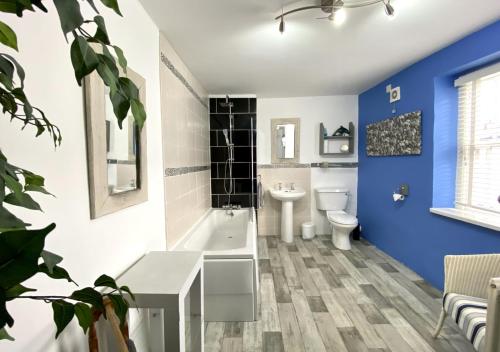 a bathroom with blue walls and a toilet and a sink at Cockle Cottage in Appledore