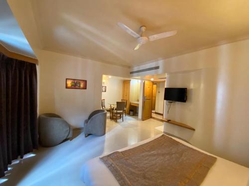 a bedroom with a bed and two chairs and a tv at HOTEL ORCHARD INN in Pune