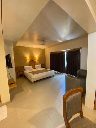 a large bedroom with a bed and a couch at HOTEL ORCHARD INN in Pune