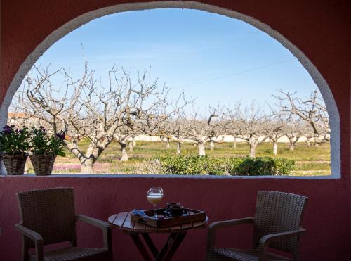 an arched window with a table and chairs and trees at Oinopia Apartments in Aegina Town