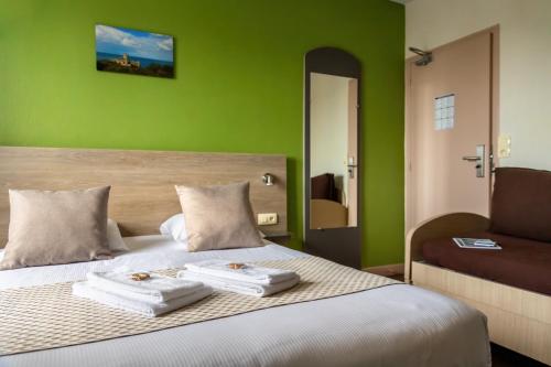 een slaapkamer met groene muren en een bed met 2 handdoeken bij Le Bon Cap in Plurien
