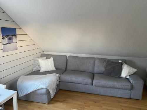 a living room with a gray couch with pillows at Stuga Lotte in Billdal