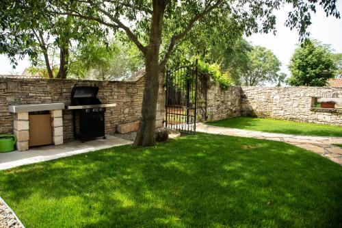 a backyard with a stone wall and a tree at Vileta Juraga in Bale