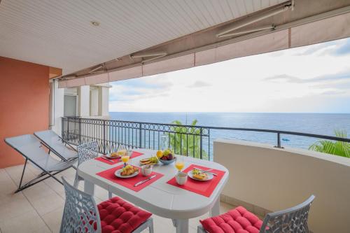 une table blanche et des chaises sur un balcon avec l'océan dans l'établissement Admiral Plaza, Superbe 2P vue mer au coeur de Menton, à Menton