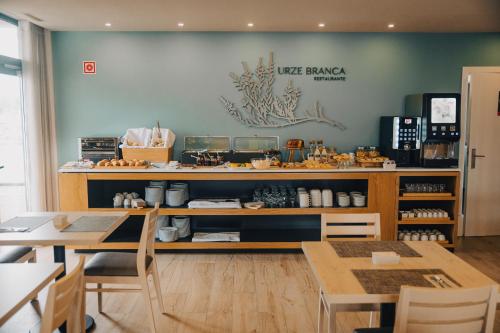 a restaurant with two tables and a counter with food at Meu Hotel Porto Gandra in Paredes