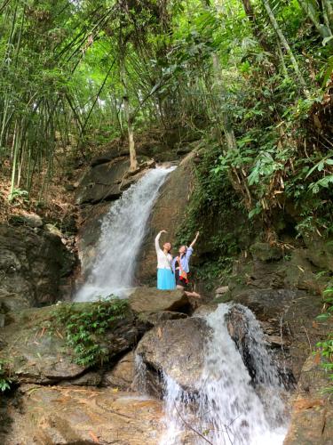 two people standing in front of a waterfall at Homestay Khoáng nóng Thông Nguyên in Nam Giang
