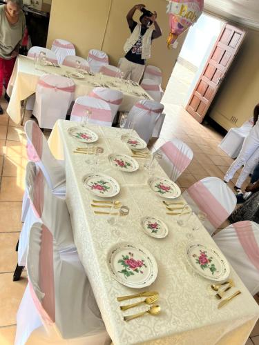un lungo tavolo con tavoli bianchi e sedie bianche di Executive Guesthouse a Vereeniging