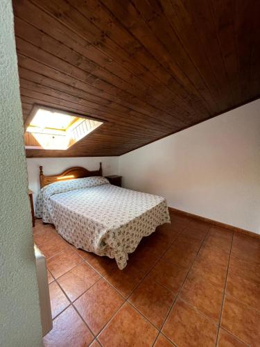 1 dormitorio con 1 cama con techo de madera en los hubios, en Arroyo Frío