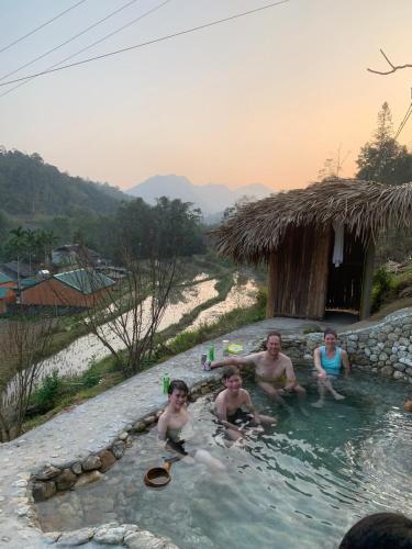 a group of people sitting in a swimming pool at Homestay Khoáng nóng Thông Nguyên in Nam Giang