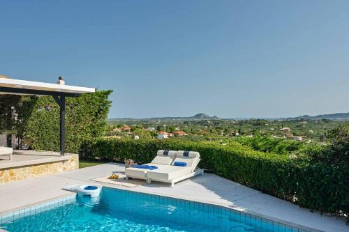 a swimming pool with a white couch and a chair next to a swimming pool at Sun Villa View in Lithakia