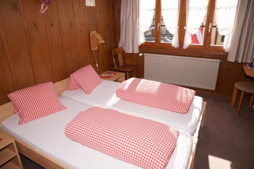 a bed with four red and white pillows on it at Gasthaus zum Sternen in Andermatt