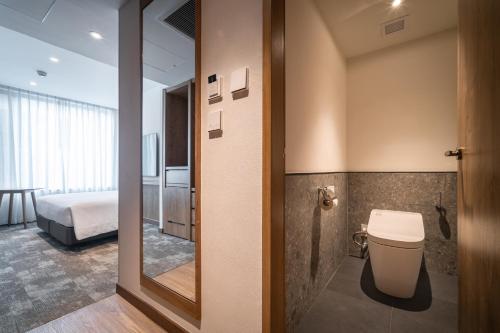 a bathroom with a toilet and a bed in a room at Sotetsu Grand Fresa Bangkok in Bangkok