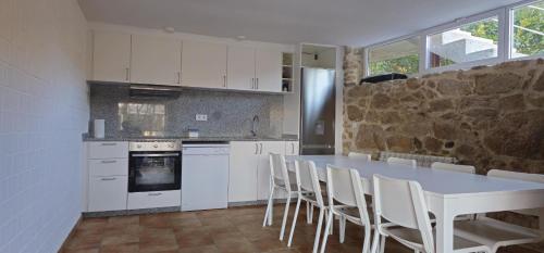 a kitchen with a table and chairs and a stone wall at Casa Gil - AL in Valença