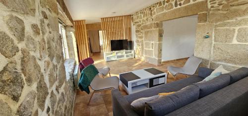 a living room with a couch and a stone wall at Casa Gil - AL in Valença