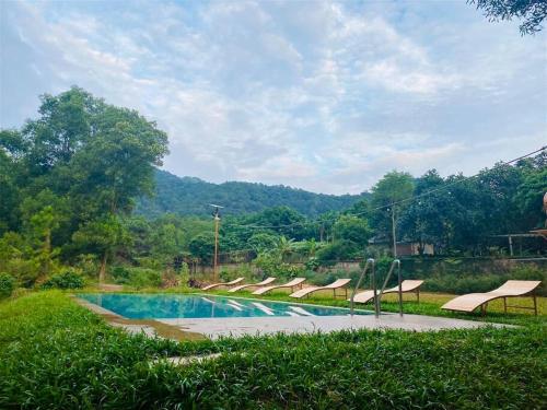 a swimming pool with lounge chairs and a mountain at Căn Bali (Moon Villa Sóc Sơn) in Hanoi