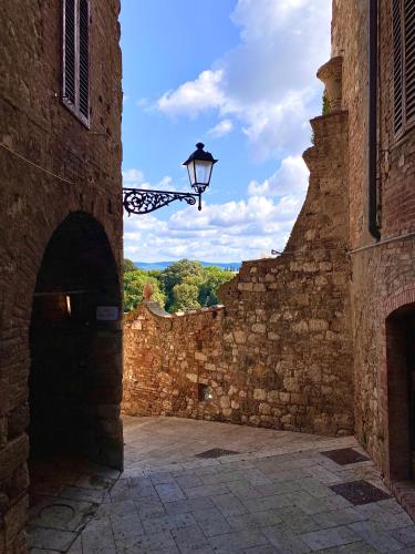an alley with an old stone wall with a street light at La Torre di Canonica in Colle Val D'Elsa
