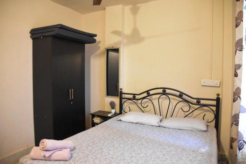 a bedroom with a bed with two white pillows and a black cabinet at Valerys Nest Bogmalo - Private villa near the beach and Dabolim airport in Bogmolo