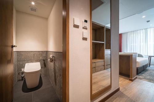 a bathroom with a toilet and a room with a bed at Sotetsu Grand Fresa Bangkok in Bangkok