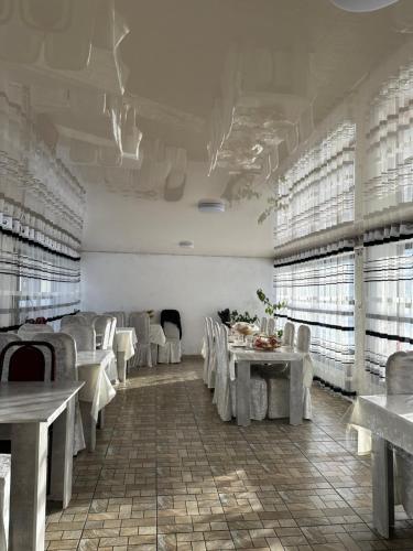 a dining room with white tables and white chairs at Dolinka Lodge in Dzhergalan