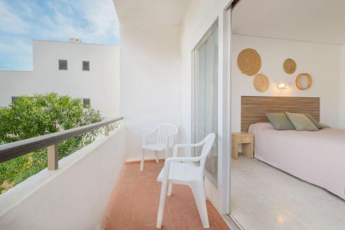 a white bedroom with a bed and a balcony at azuLine Hotel Mediterráneo in Santa Eularia des Riu