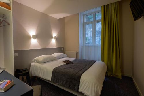 a hotel room with a bed and a window at Hôtel Du Port in Morlaix