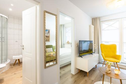 baño con TV y silla amarilla en Fewo Auszeit im Haus Strandburg en Binz