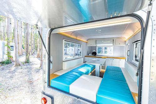 uma vista interior de uma caravana com bancos azuis em glampark FREE AND EASY CAMP RESORT　三重県 em Komono