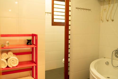 a bathroom with a red shelf next to a toilet and a tub at Ivory Falls Villa in Di Linh