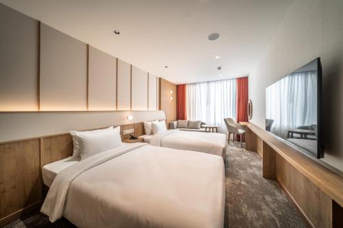 a hotel room with two beds and a flat screen tv at Sotetsu Grand Fresa Bangkok in Bangkok