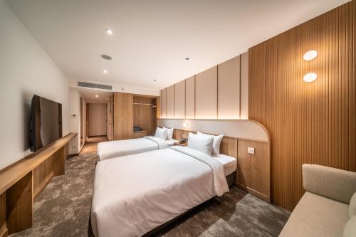 a hotel room with two beds and a tv at Sotetsu Grand Fresa Bangkok in Bangkok