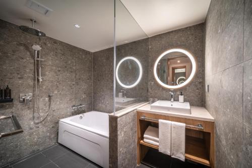 a bathroom with a tub and a sink and a mirror at Sotetsu Grand Fresa Bangkok in Bangkok