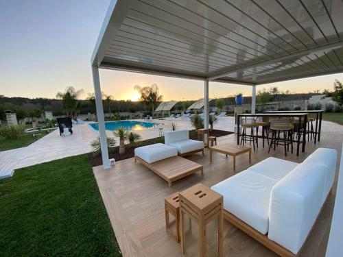 a patio with white furniture and a table and a pool at Villa Anna - Suites & Events in Specchia
