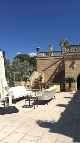 a patio with a stone bridge with tables and chairs at Villa Anna - Suites & Events in Specchia