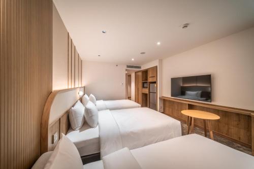 a hotel room with two beds and a television at Sotetsu Grand Fresa Bangkok in Bangkok